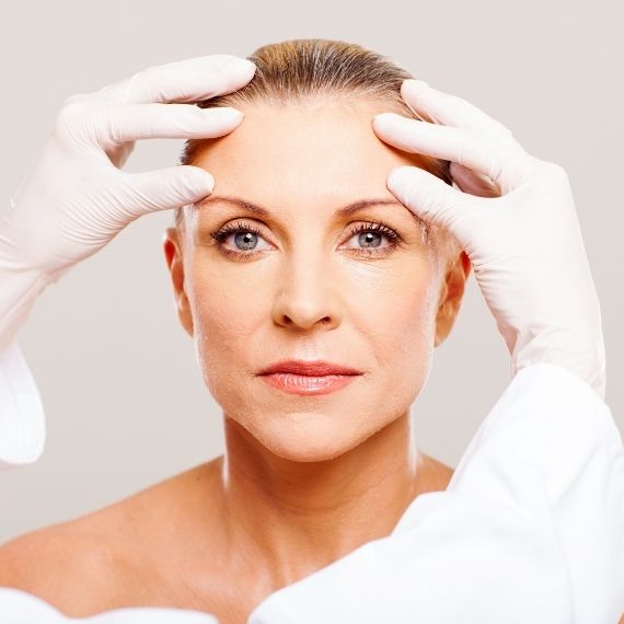 cosmetic surgery and surgeon holding forehead
